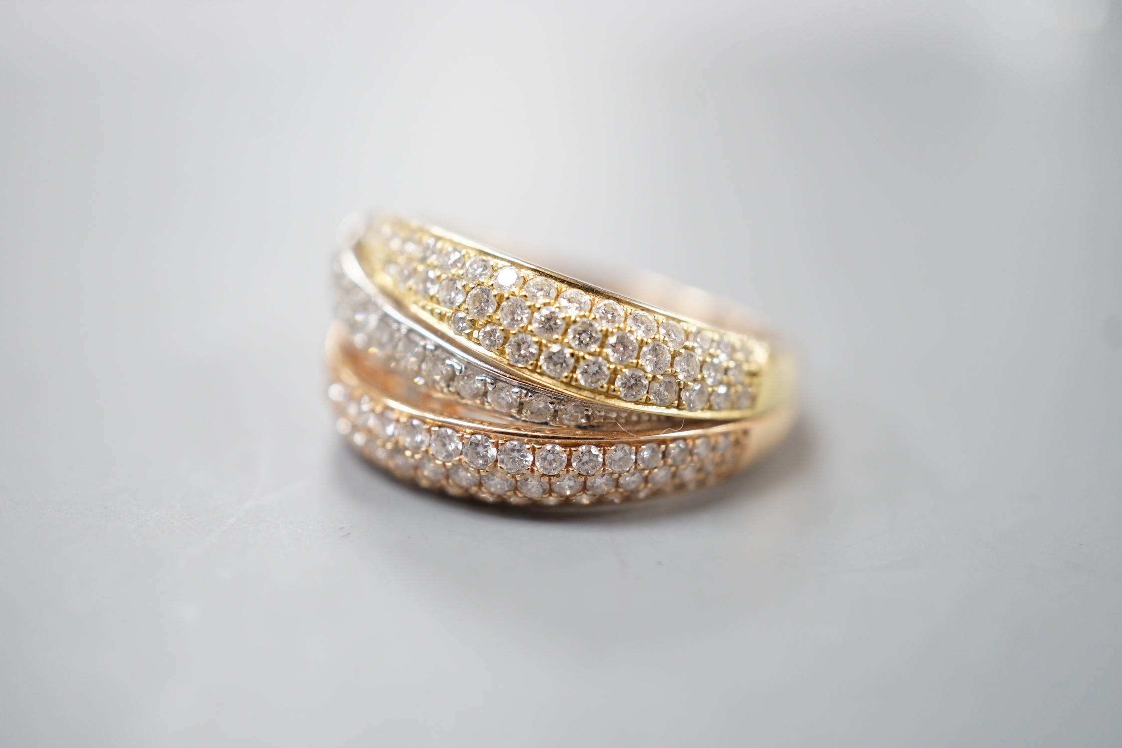 A modern three colour 18ct gold and diamond chip set triple band crossover ring, size O, gross weight 7 grams.